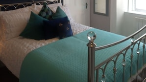 Ein Schlafzimmer mit Bett, Kopfteil, Fenster und Tür.