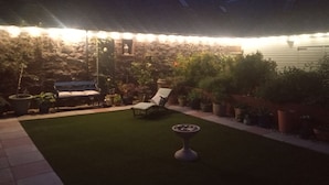 Eine Terrasse mit Rasenfläche, Sitzgelegenheiten und Kübelpflanzen.