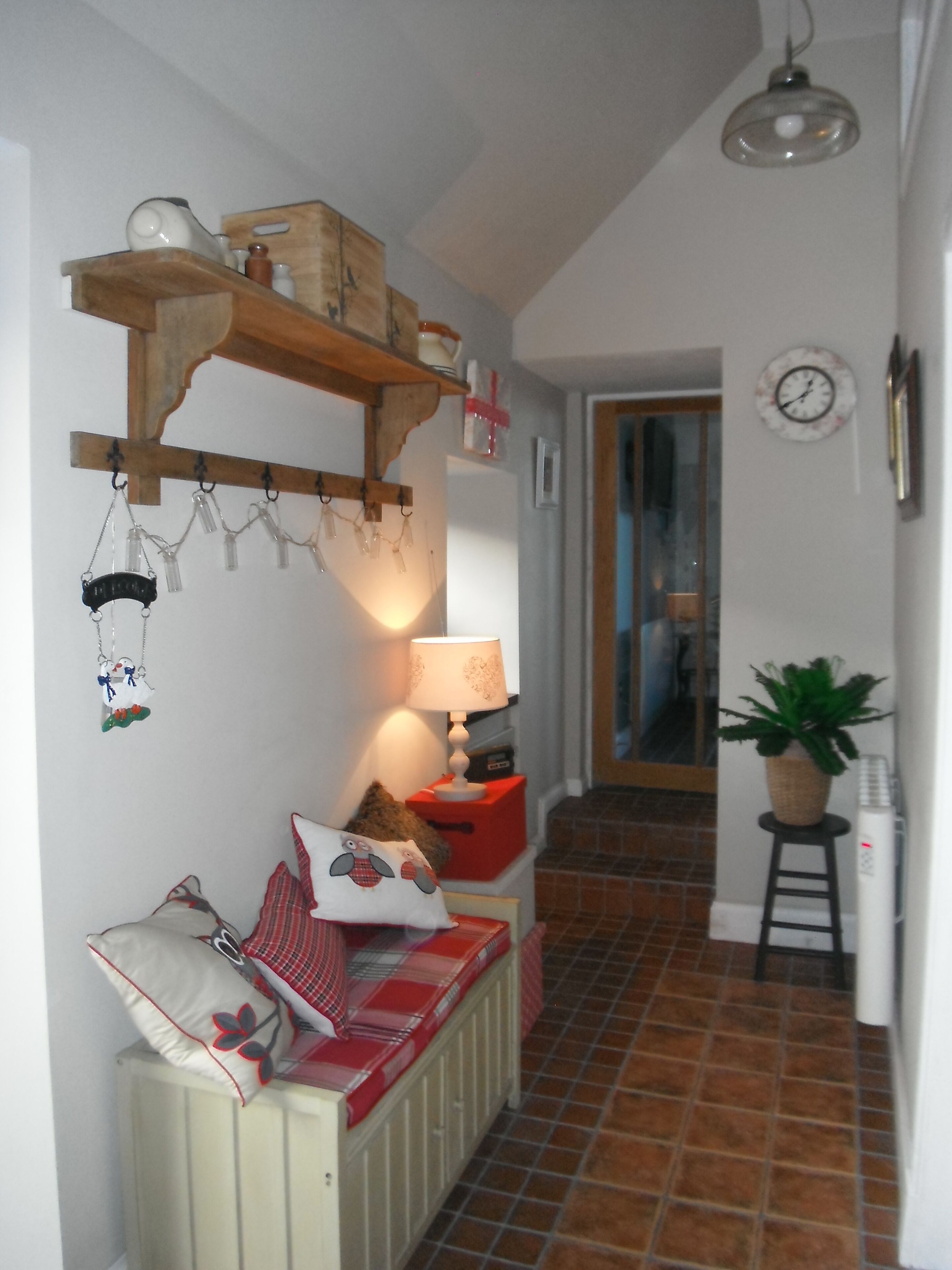 Ein gemütlicher Flur mit einem Holzregal, das verschiedene Gegenstände, eine Lampe und eine Heizung beherbergt.
