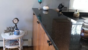 A kitchen with wooden cabinets, a black countertop, a small white table with a decorative item, and wall decorations including a star and a shell.