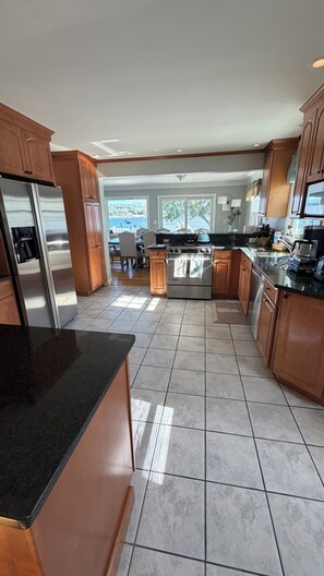 A modern kitchen with stainless steel appliances, wooden cabinets, and a large island.