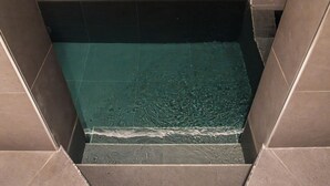 A bathtub with a clear water surface, surrounded by dark tiles. - Hotel Leonessa  (Brescia)