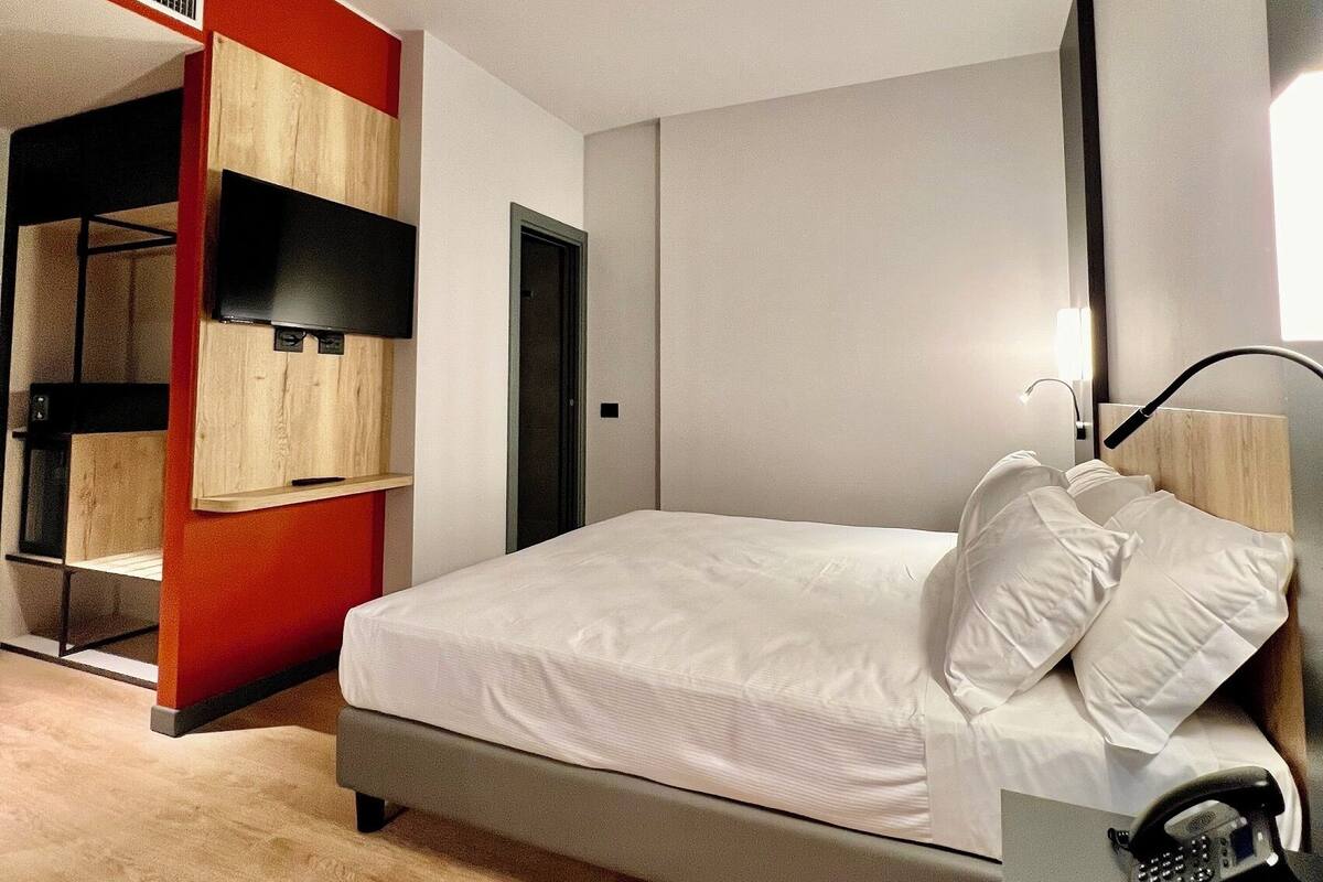 Un dormitorio moderno con una cama, un teléfono y un televisor.