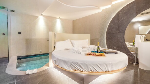 A modern hotel room with a curved bed, a small pool, and a separate bathroom area. - Hotel Leonessa  (Brescia)