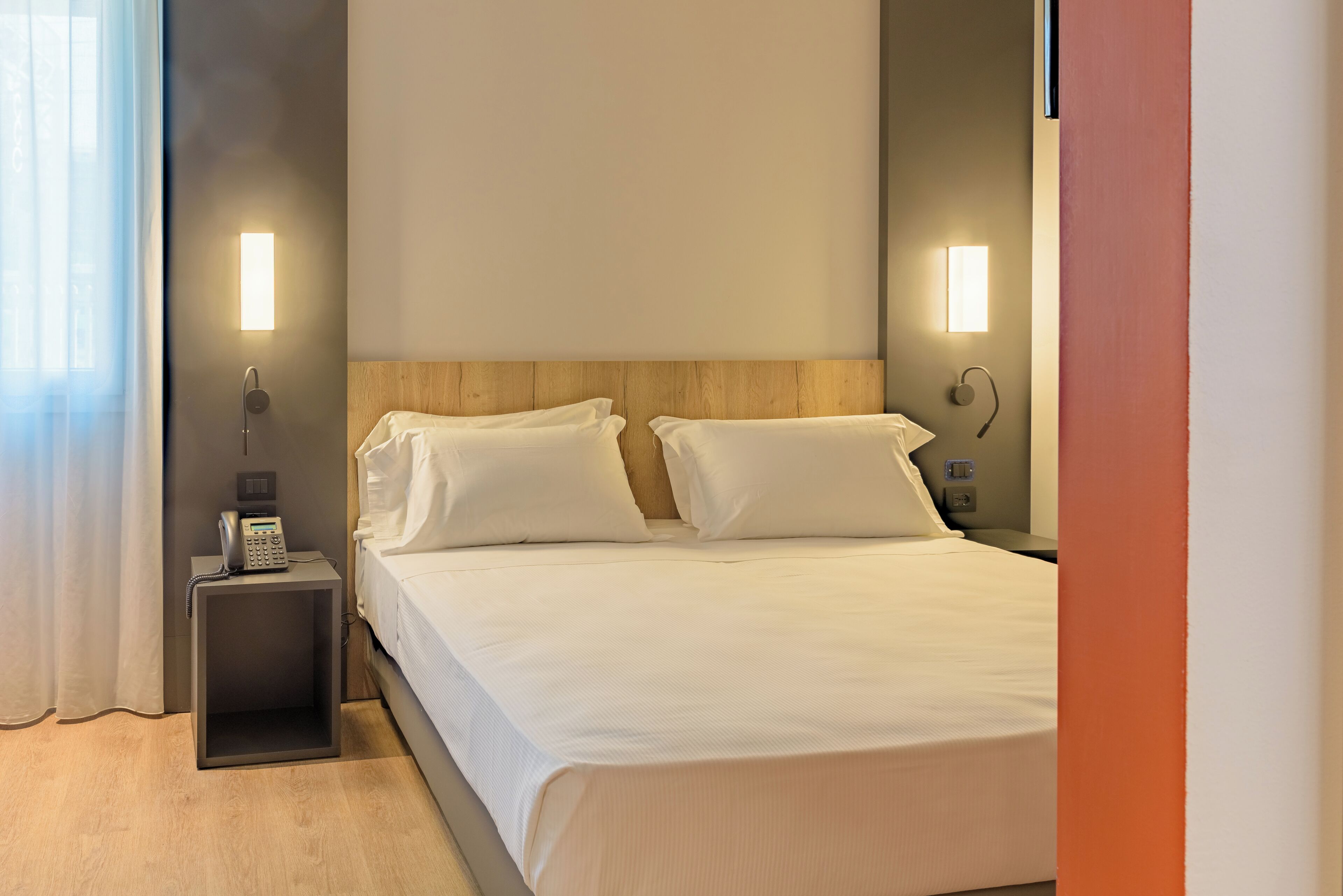 Une chambre d’hôtel avec un lit, des tables de chevet et un téléphone.
