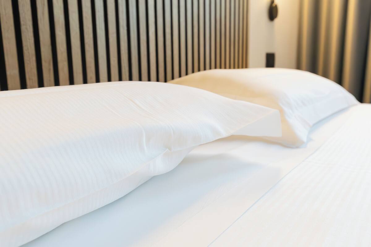 Una cama bien hecha con sábanas blancas y un cabecero de madera.