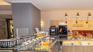 A buffet area with various food options, a coffee machine, and a wall displaying coffee and cappuccino options. - Hotel Leonessa  (Brescia)