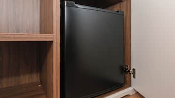 Un meuble de rangement noir doté d’une poignée métallique, placé dans un meuble en bois dont la base est blanche.