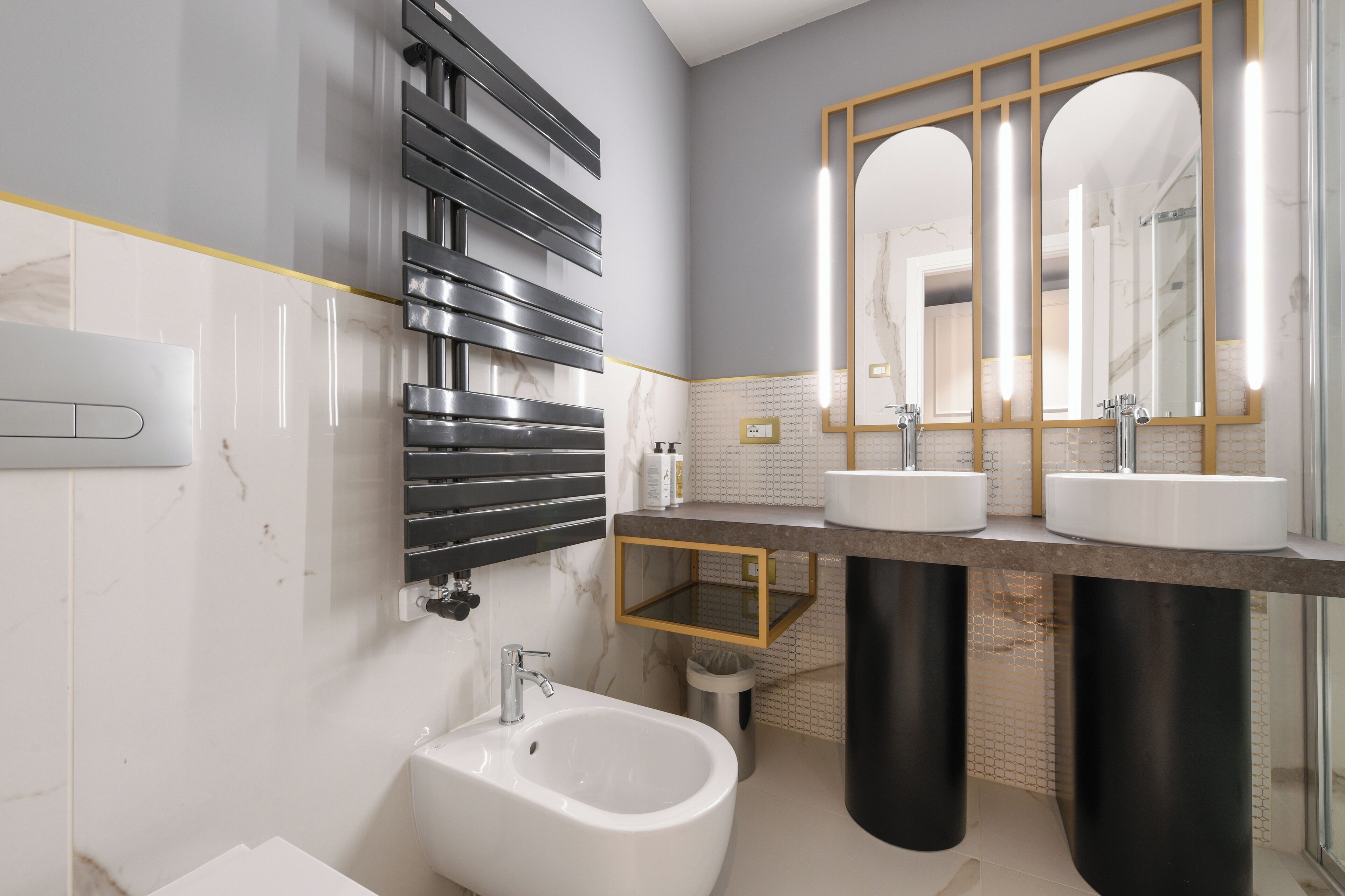 A modern bathroom with a bidet, two sinks, and a large mirror.