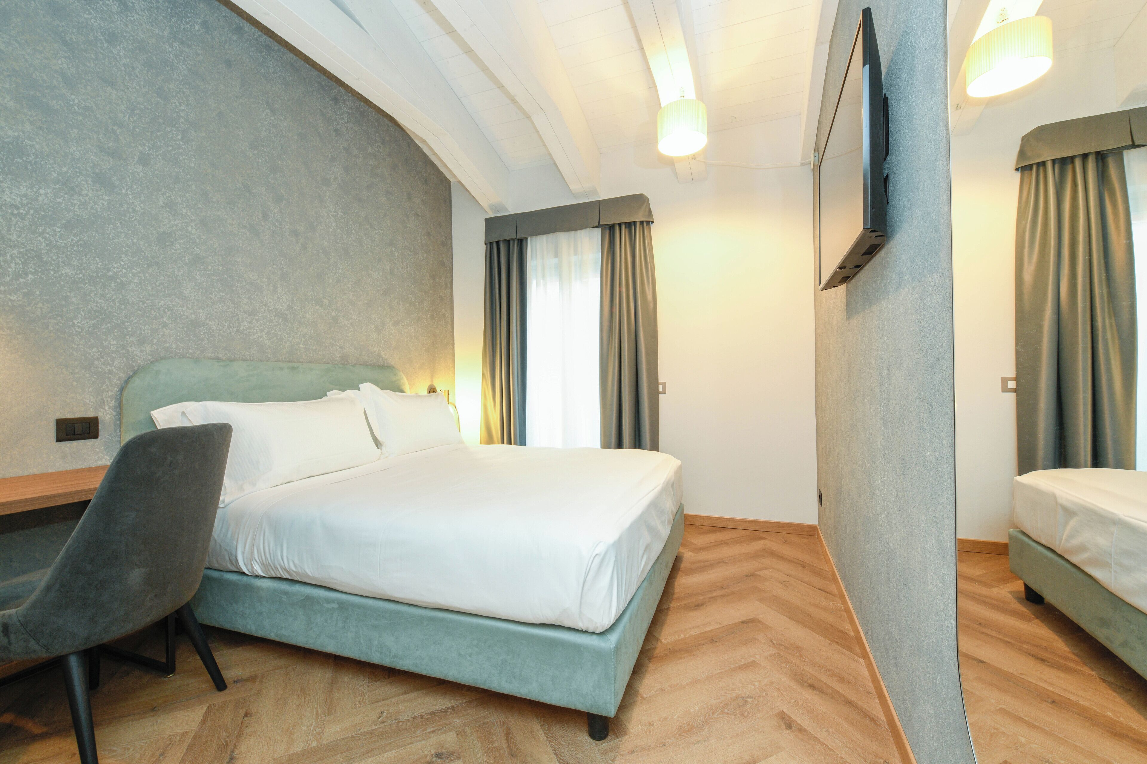 A hotel room with a bed, a desk, and a chair.