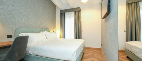 A hotel room with a bed, a desk, and a chair.