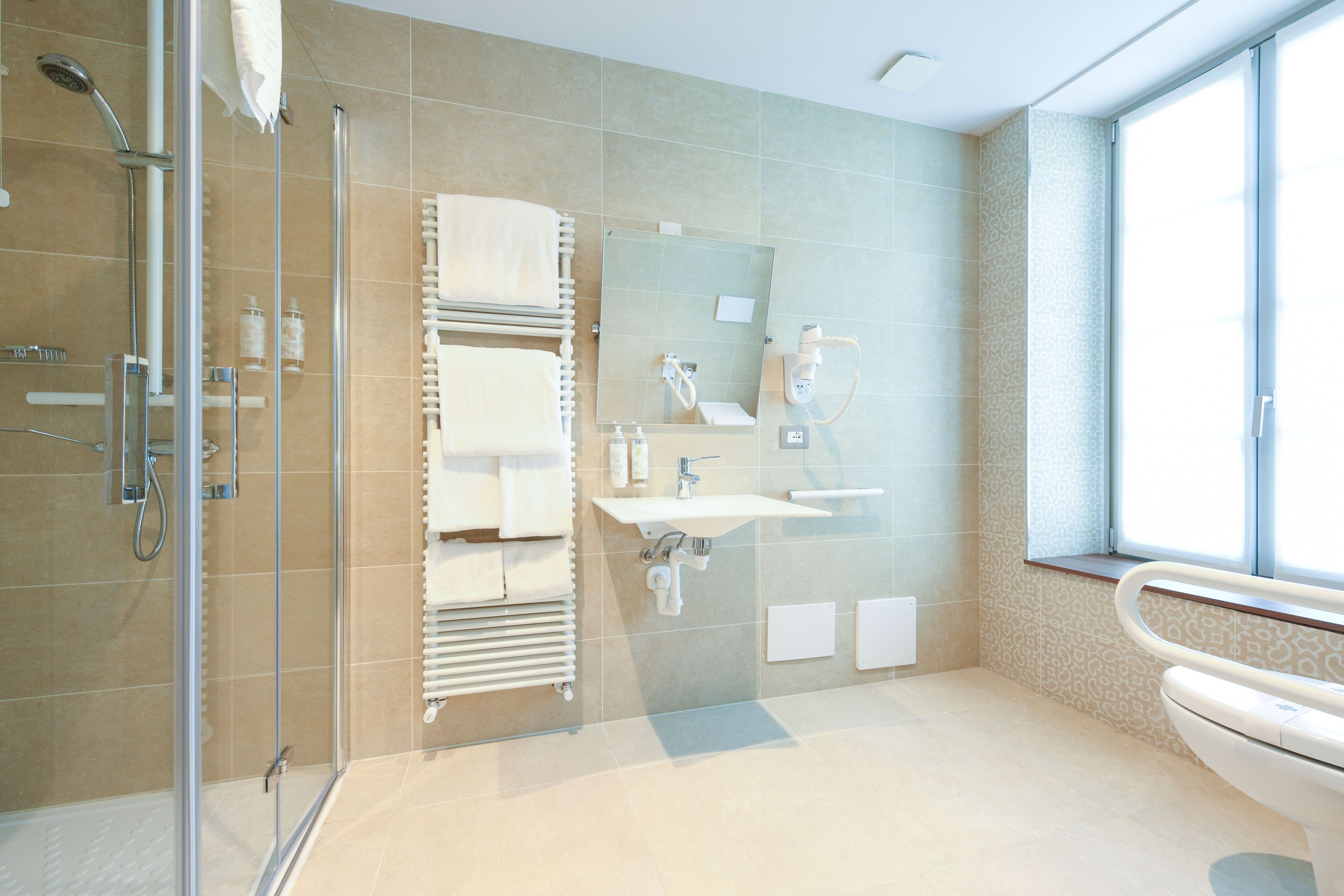 A modern bathroom with a glass shower enclosure, a white sink, and a large mirror.