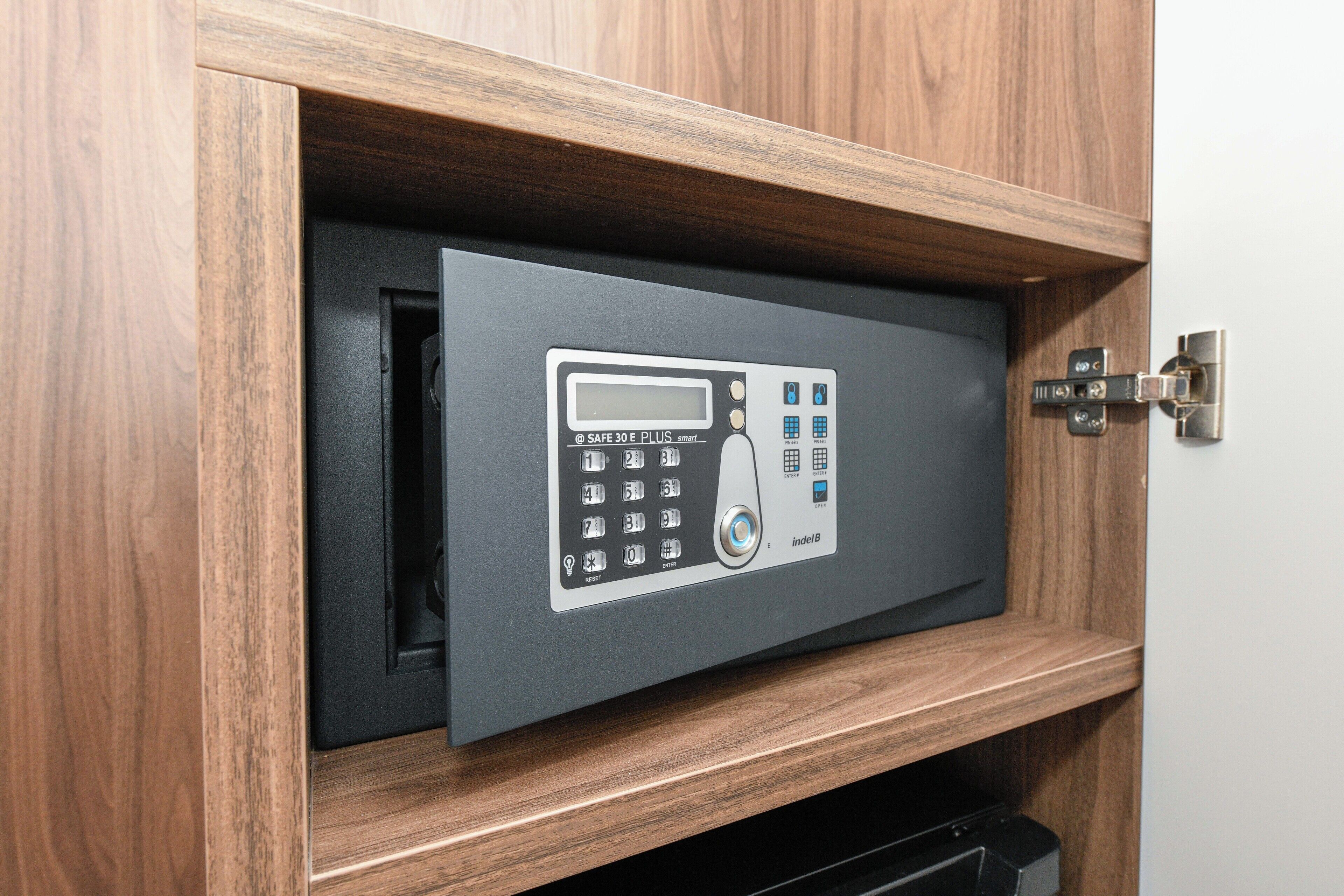 A safe with a keypad and a digital display inside a wooden cabinet.