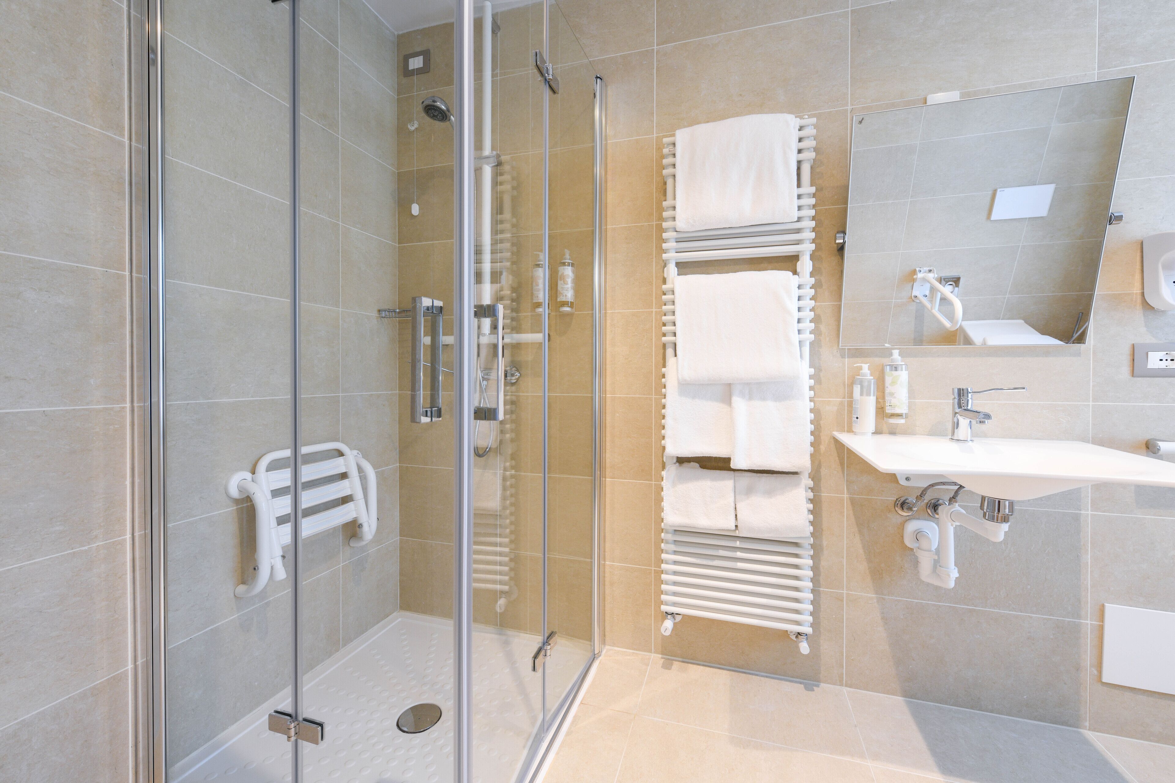 A modern bathroom with a glass shower enclosure, a white sink, and a large mirror.