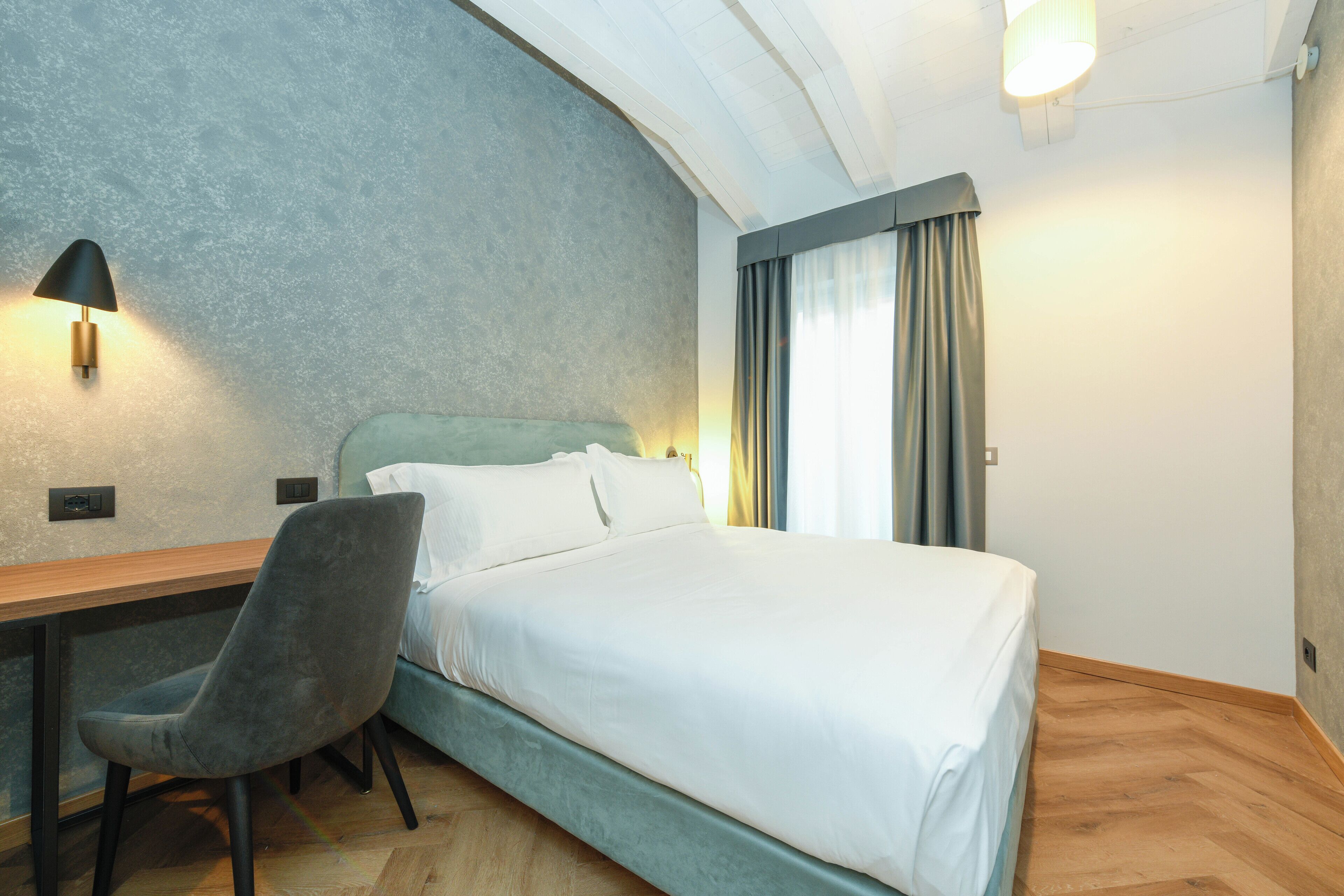 Een slaapkamer met een bed, een bureau en een stoel.