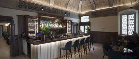 A bar area with a counter, stools, and a variety of bottles and glasses.