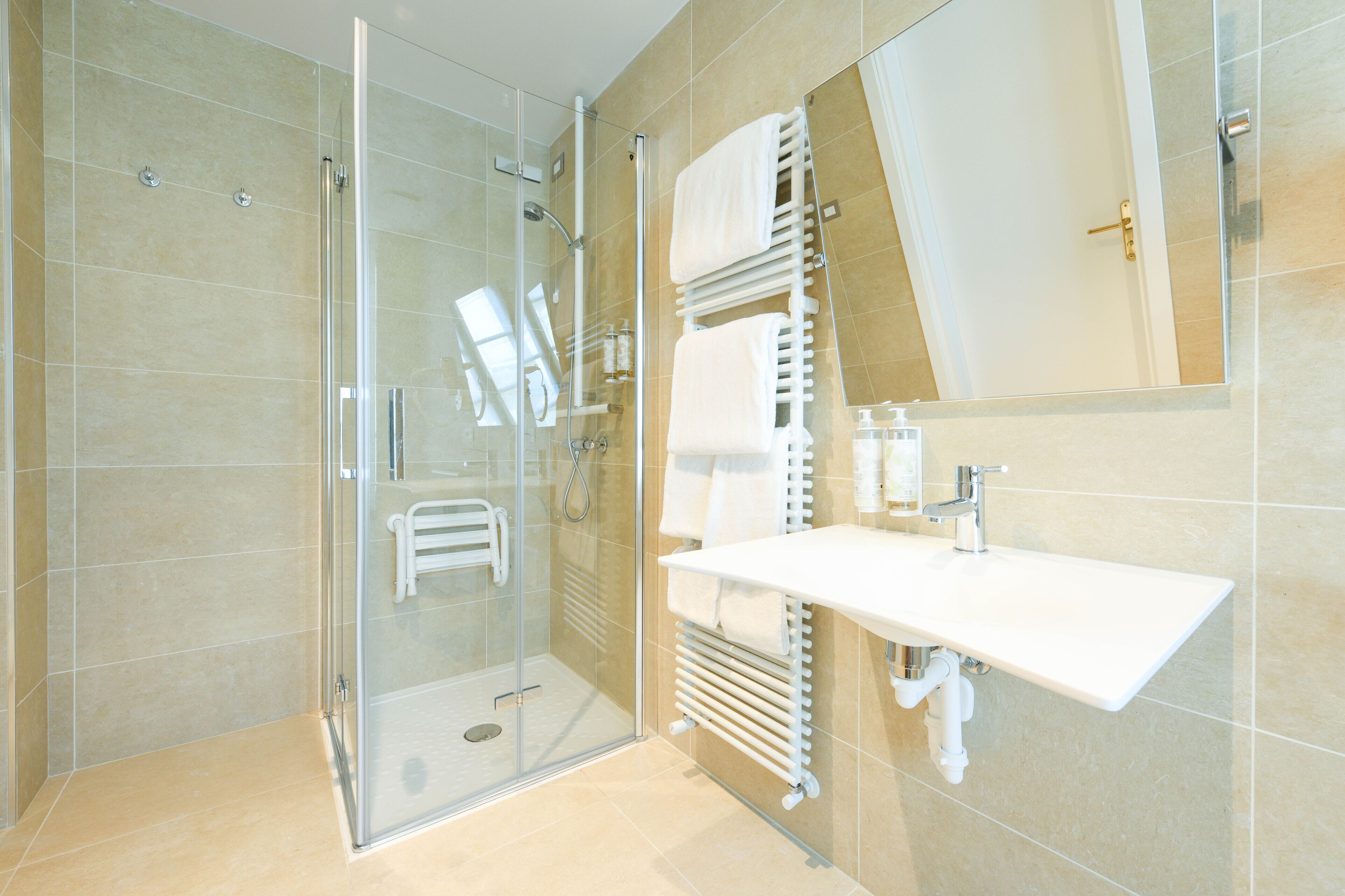 A modern bathroom with a glass shower enclosure, a white sink, and a towel rack.