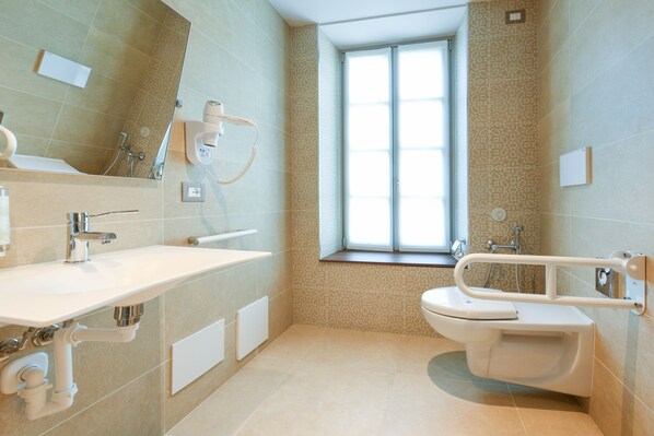 Un baño moderno con un espejo grande, un lavabo, un inodoro y una ventana.