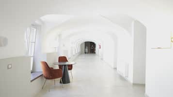 Un interno moderno e luminoso con un lungo corridoio, un tavolo rotondo con sedie e una finestra a sinistra.