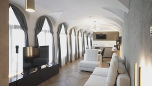Een moderne woonkamer met een flatscreen-tv, een bank en een eethoek op de achtergrond.