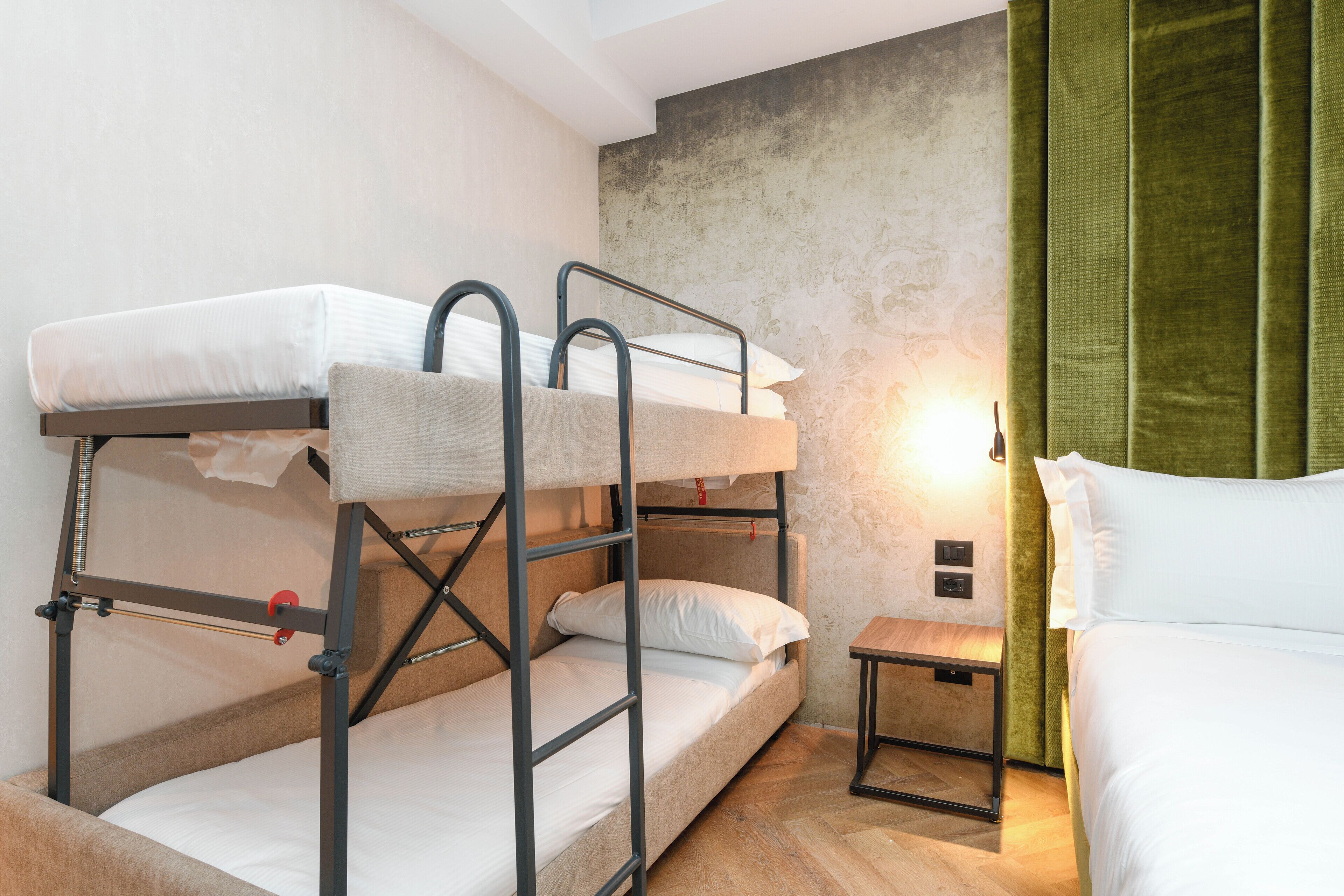 A bunk bed room with a small table and a lamp.
