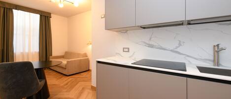 A modern kitchen with grey cabinets, a marble backsplash, and a black countertop.