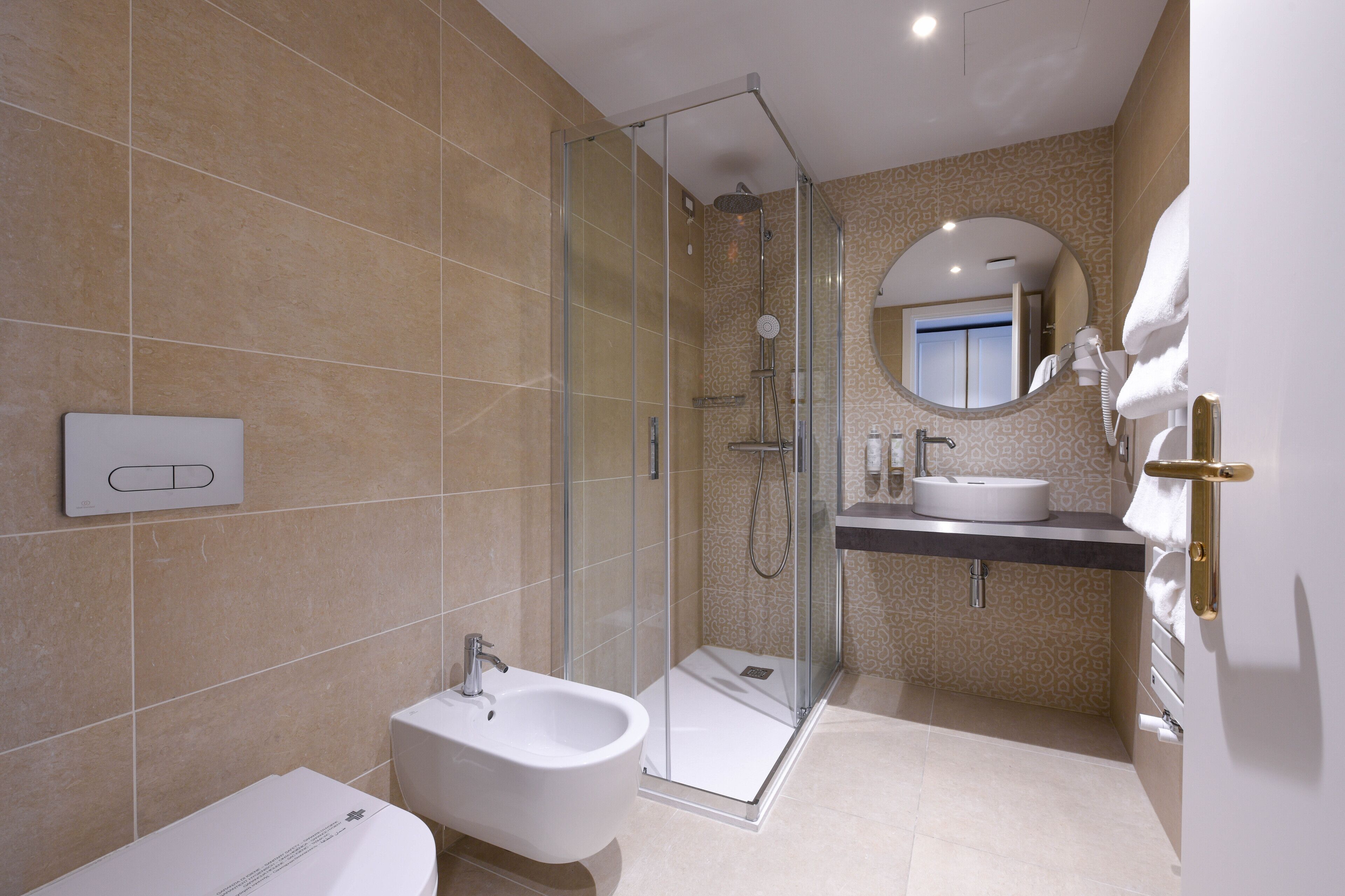 A modern bathroom with a glass-enclosed shower, a bidet, and a vanity with a sink and mirror.