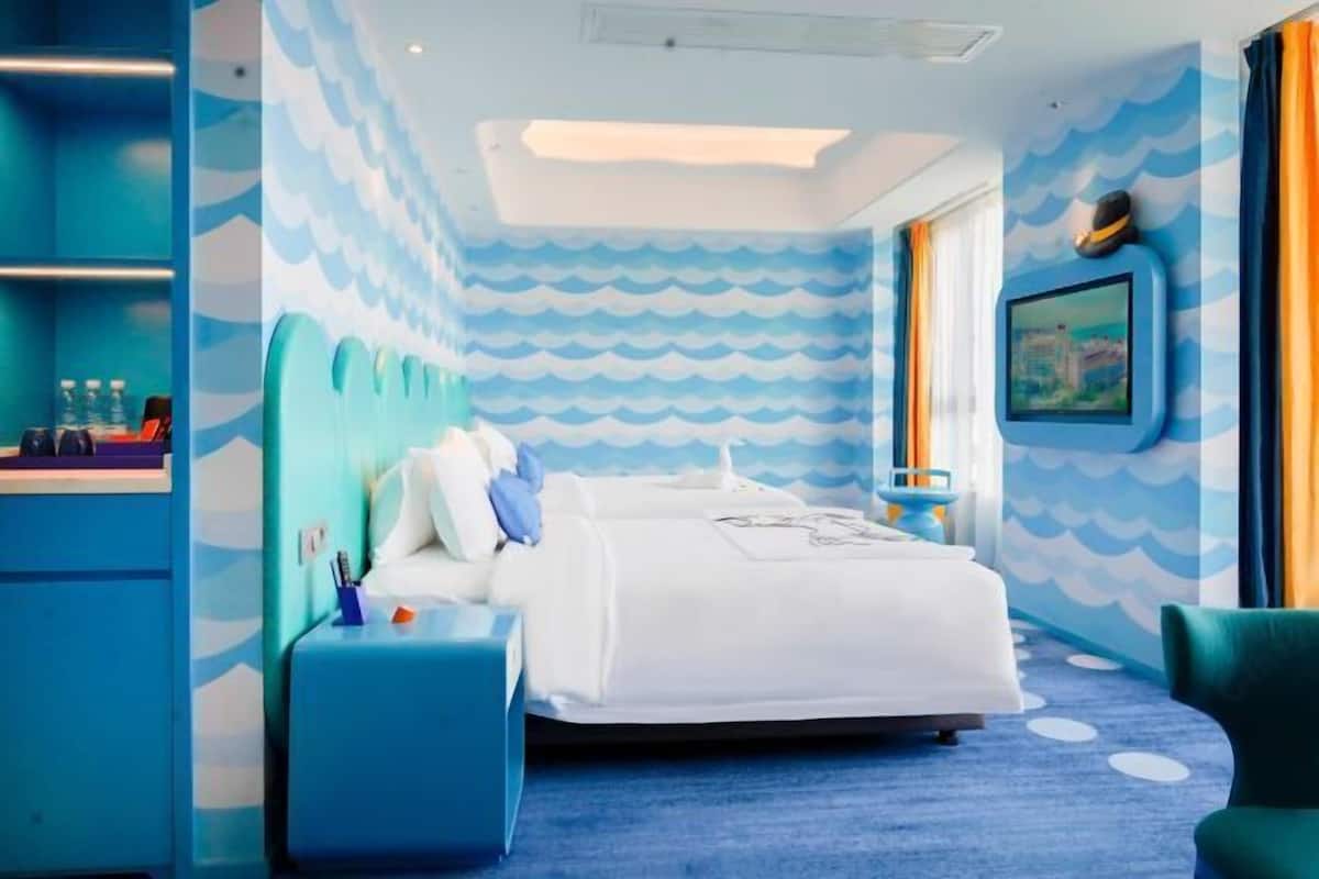 Habitación de hotel con cama, mesita de noche, una silla y una pared con un diseño de olas.