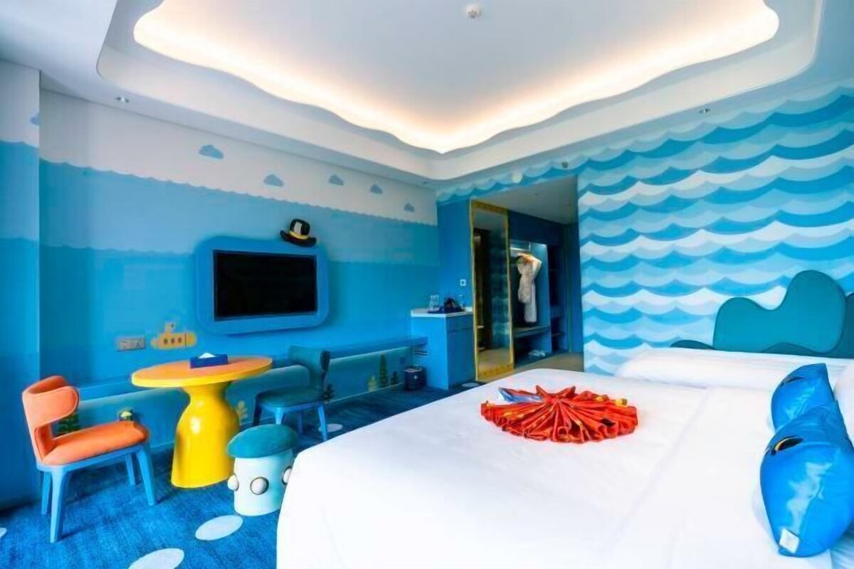 Una habitación con cama, televisión, una mesita y una silla.