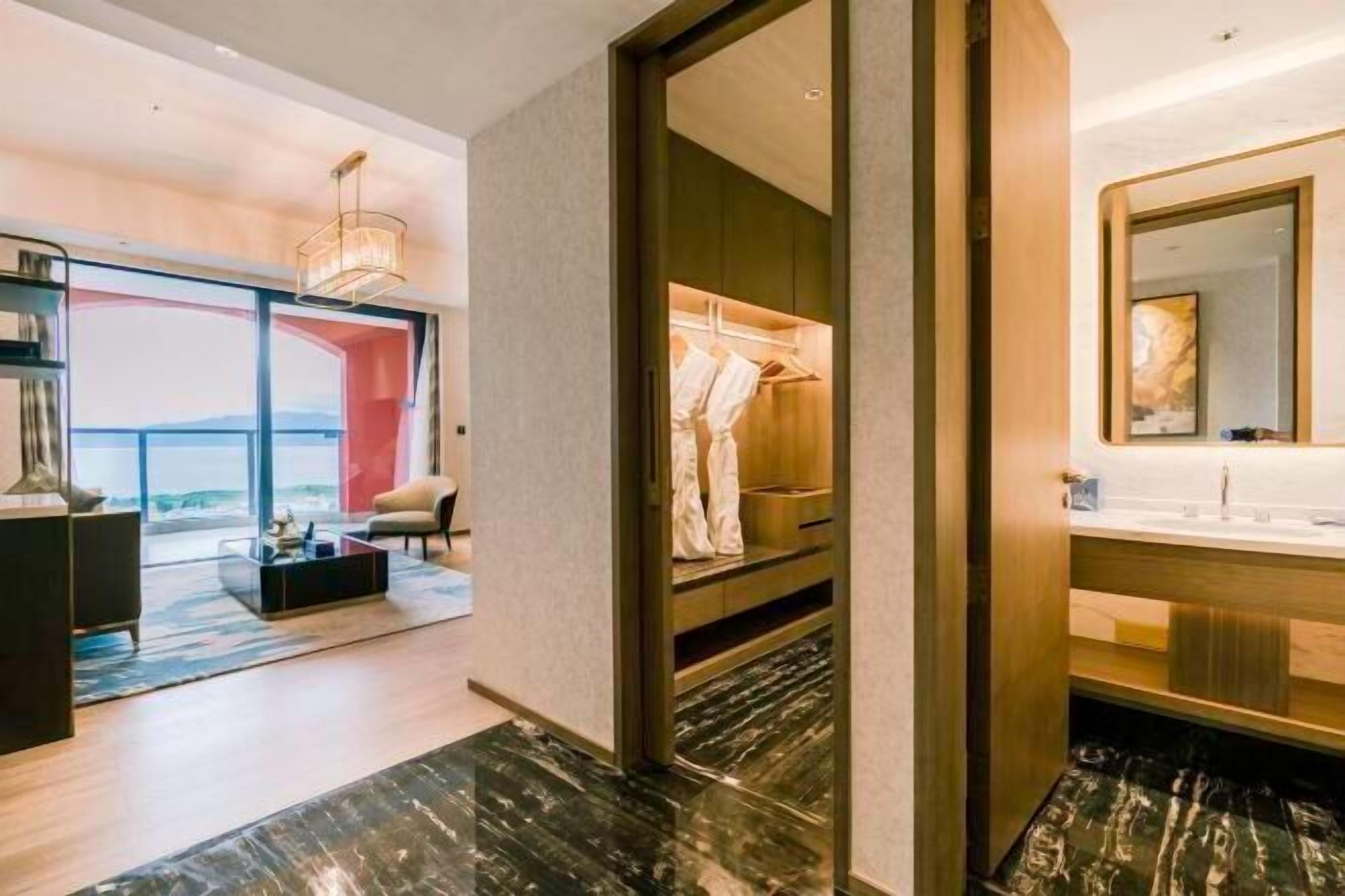 A modern hotel room with a large window, a walk-in closet, and a marble floor.