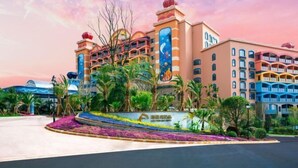 A hotel with a large, colorful facade, multiple balconies, and a landscaped garden area. - Fuxian Lake Dolphin Bay Hotel (Cambrian Town Flagship Store) (Chengjiang)