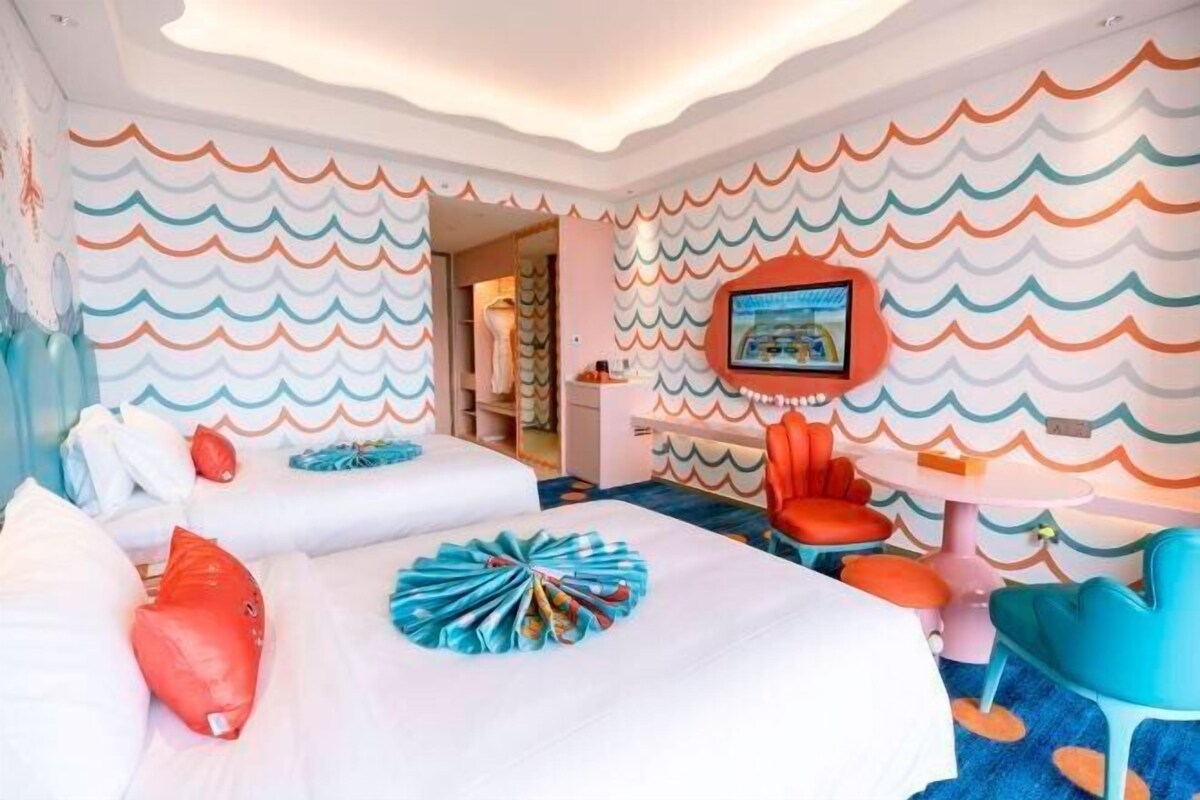 Una habitación de hotel con dos camas, televisión, escritorio y una silla.