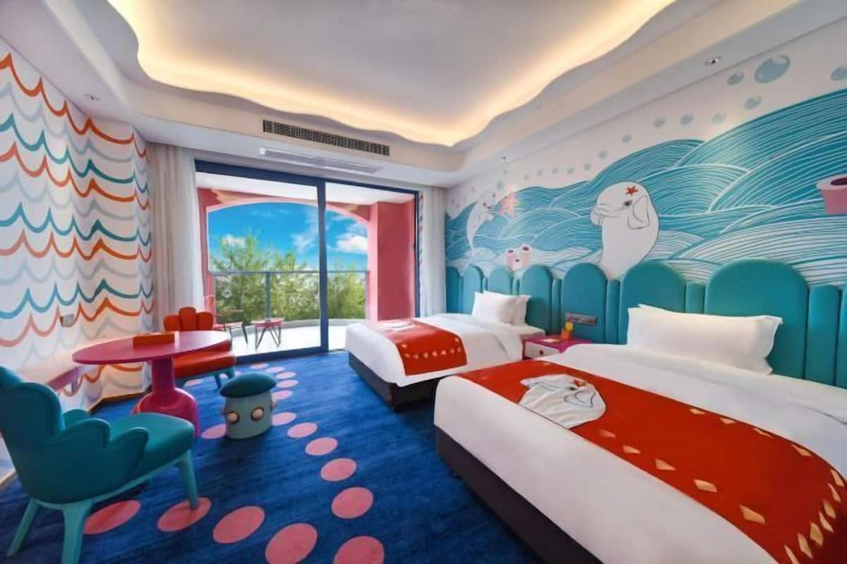 Habitación de hotel con una cama grande, zona de estar separada con una mesa y vistas a través de la puerta de cristal.
