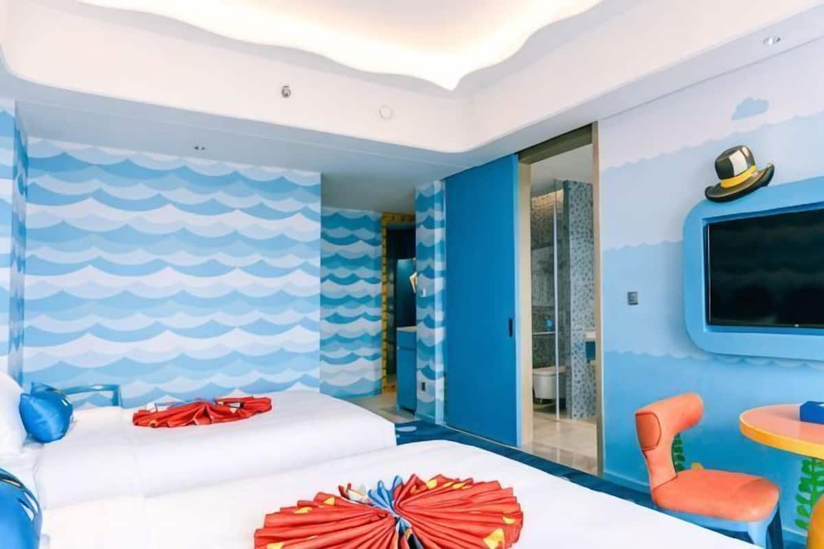 Una habitación con cama, una silla, una mesita y un televisor.