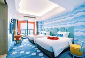 Habitación de hotel con dos camas, vista al mar y una alfombra de lunares.