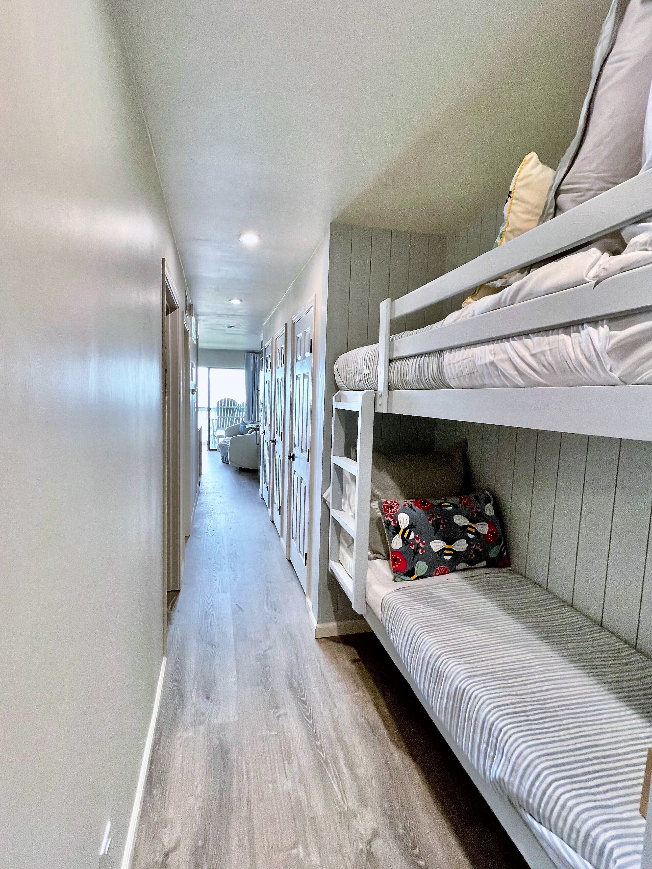 A narrow hallway with bunk beds on one side and a door leading to another room.