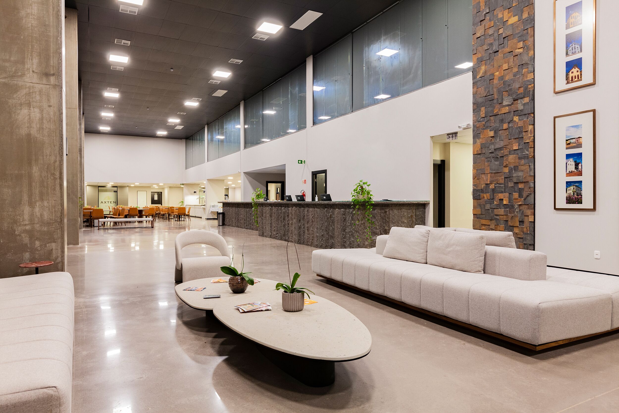 A spacious lobby with a reception desk, seating area, and a modern design featuring a stone accent wall and framed pictures.