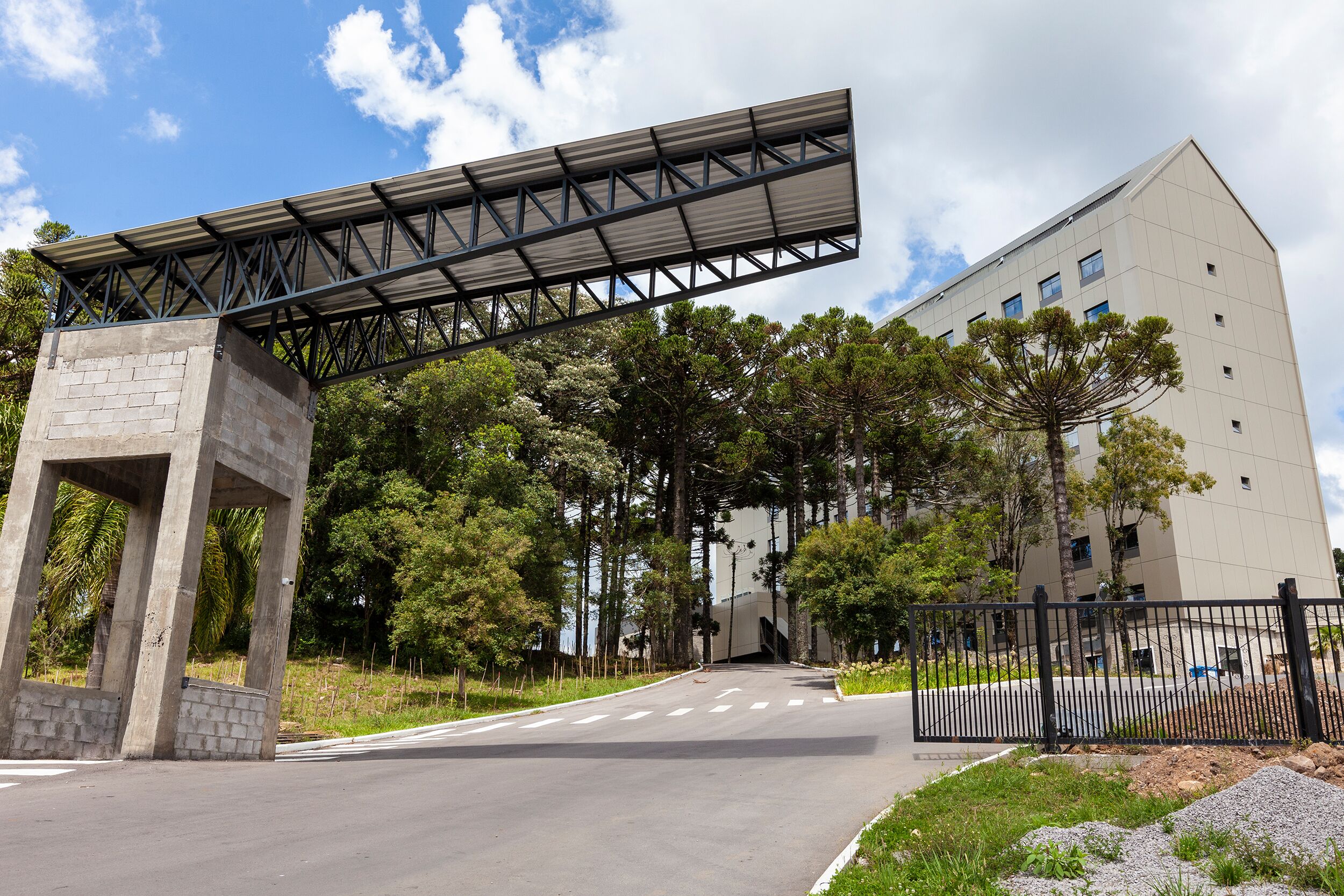 Un edificio moderno con acceso cubierto y un camino de entrada con portón.