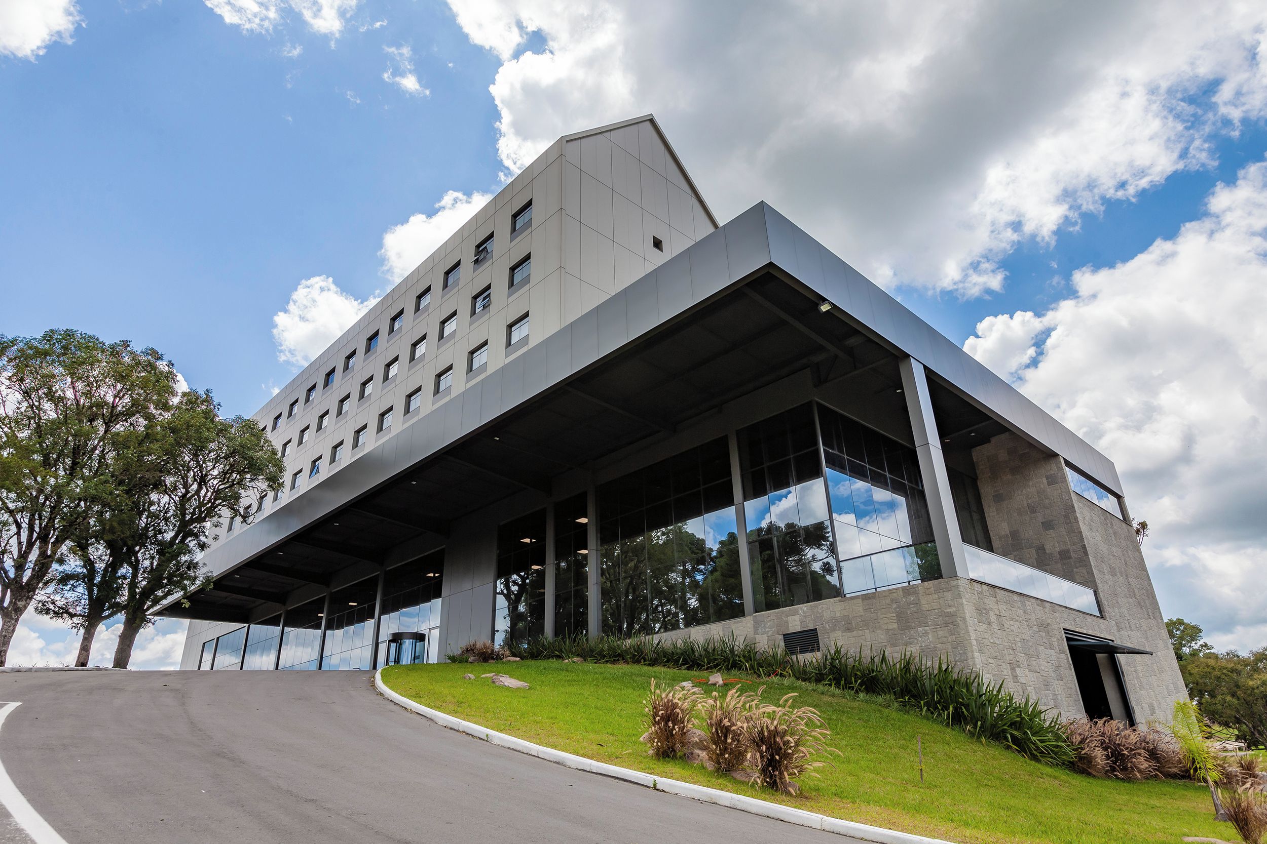 A modern building with a flat roof, large windows, and a sloped side.