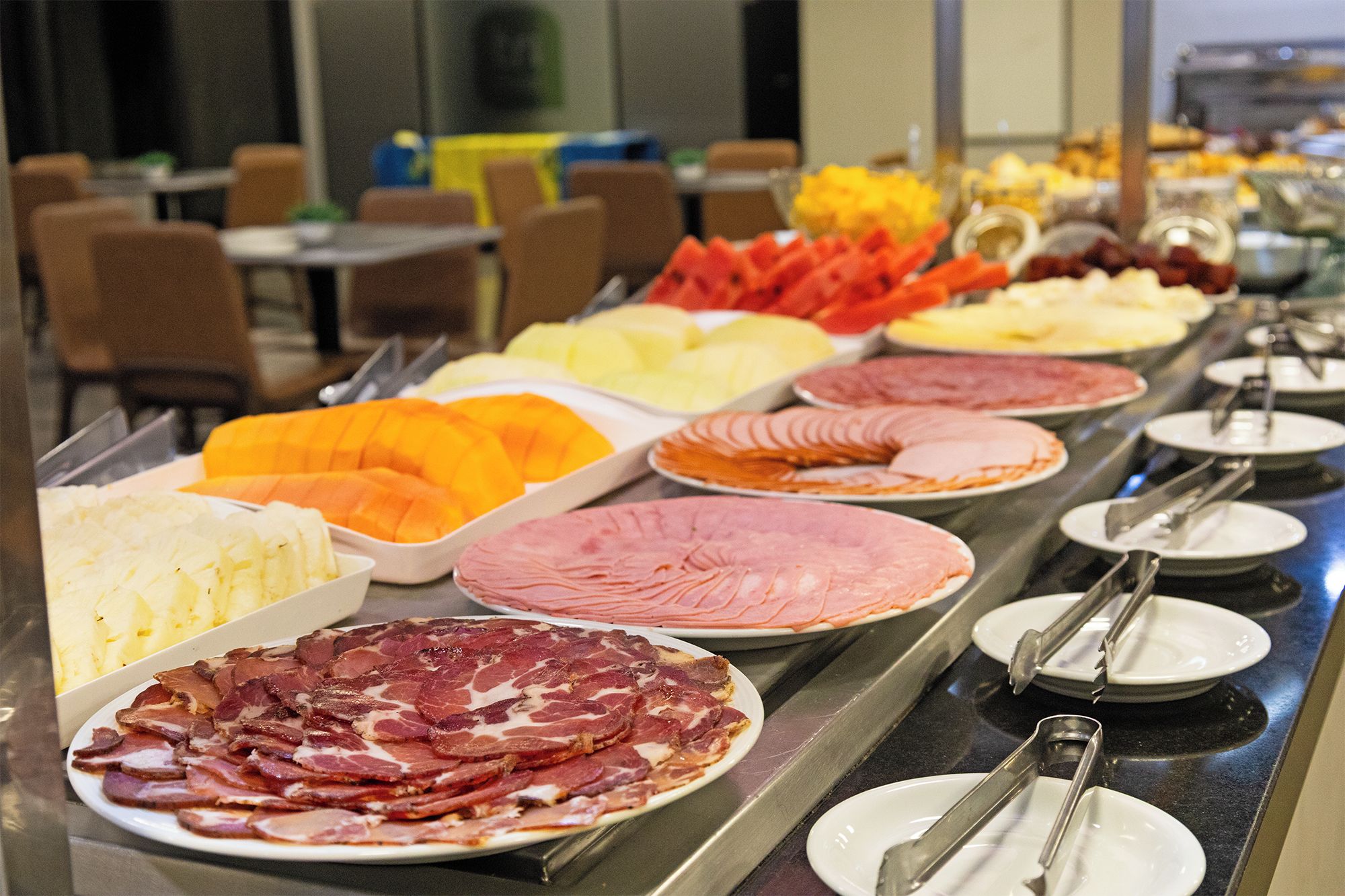 A buffet with various food items including sliced meats, cheeses, and fruits.