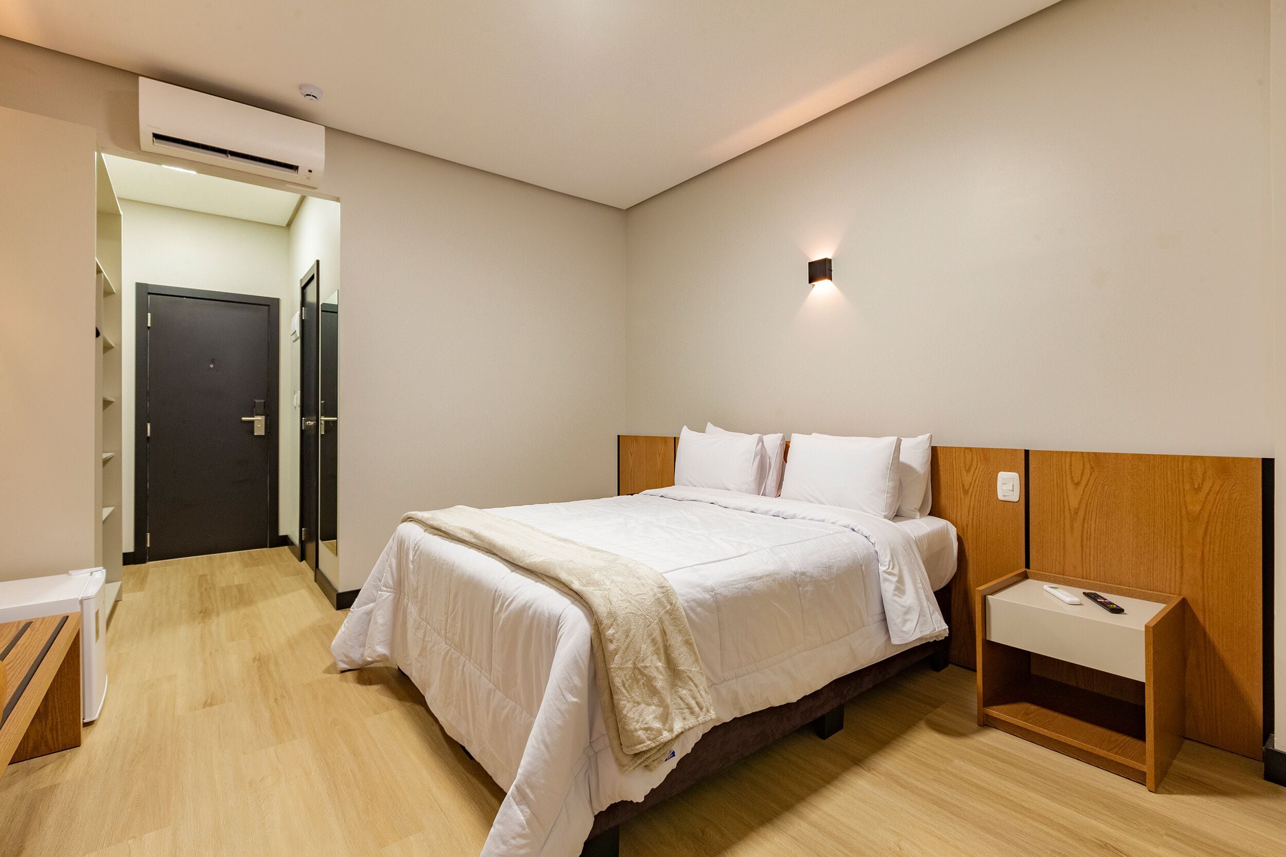 A bedroom with a bed, bedside table, and an air conditioning unit.
