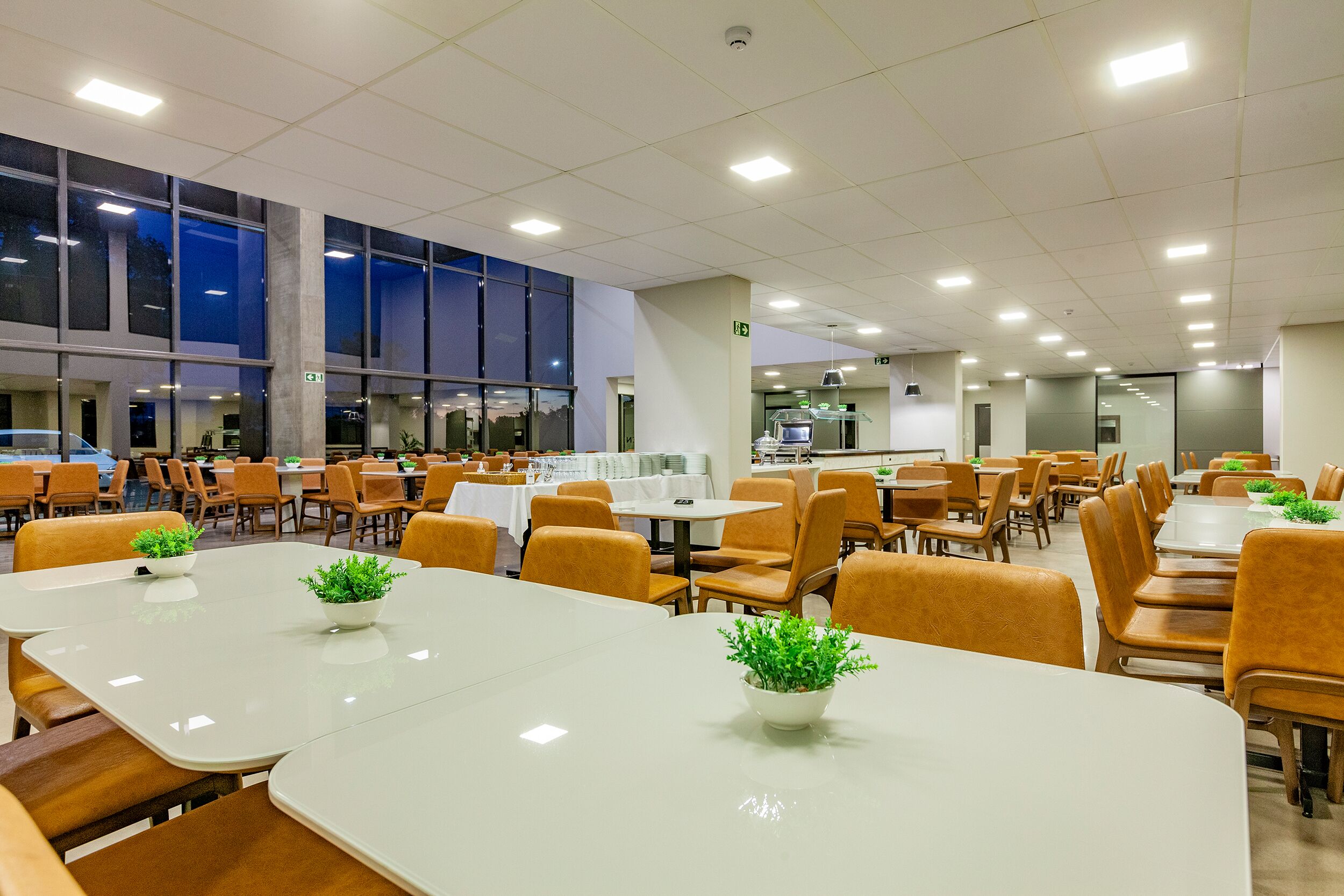 A spacious dining area with multiple tables and chairs, large windows, and a clean, modern interior.