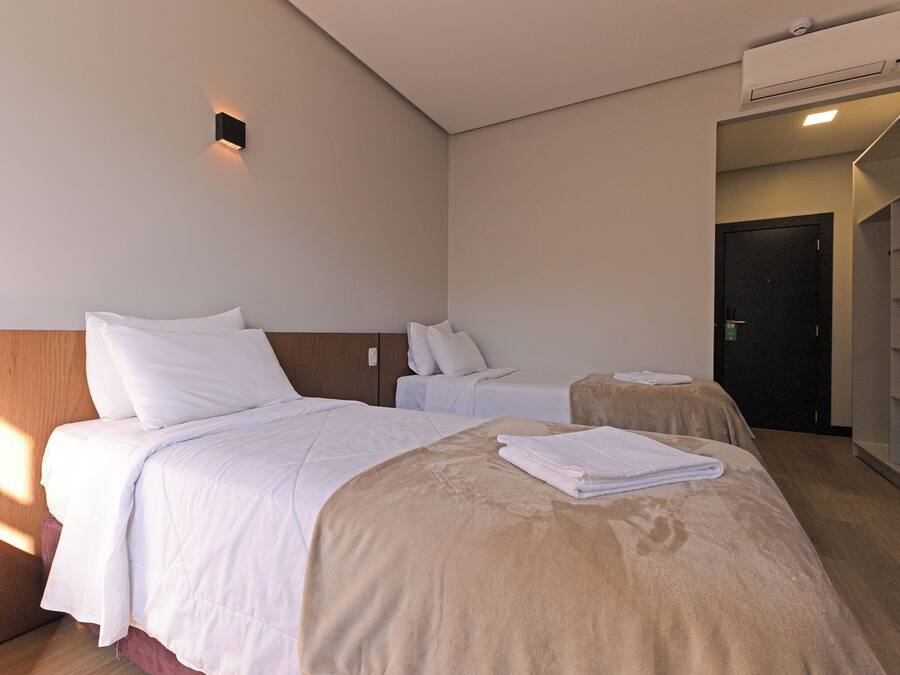 A hotel room with two beds, a wardrobe, and a bathroom.