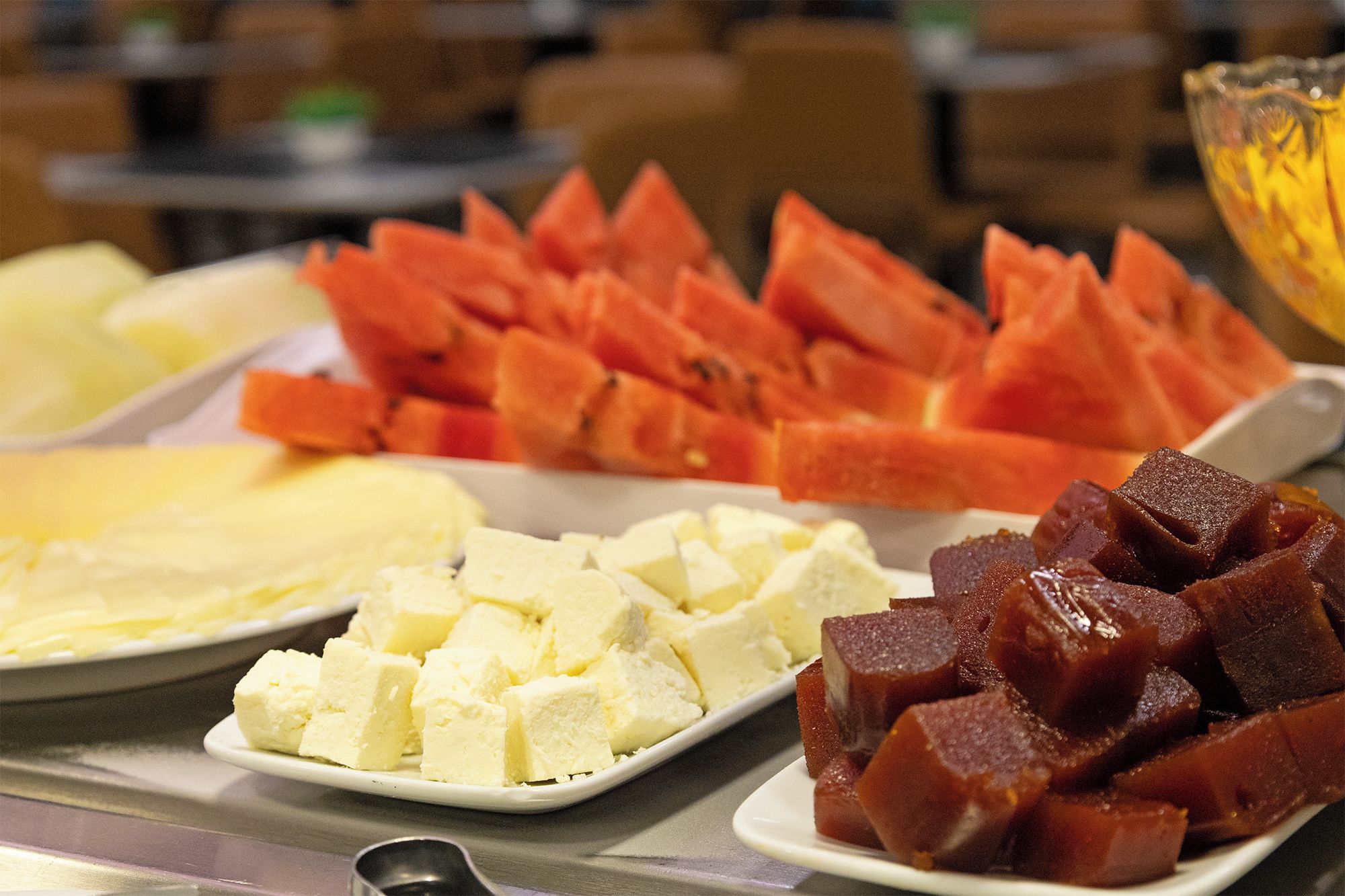 A buffet with various food items including cubed cheese, cubed meat, and sliced vegetables.