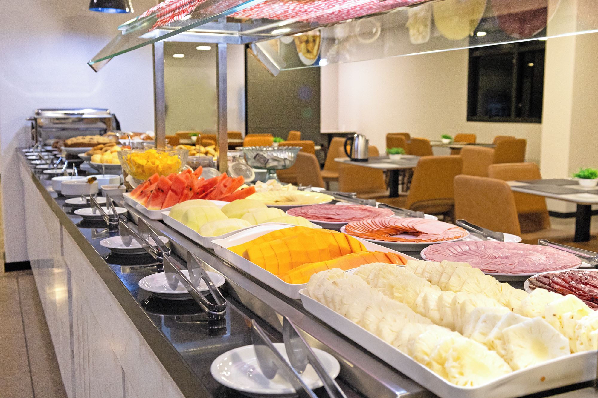 Buffet amb diverses opcions gastronòmiques, com fruita, carns i formatges.