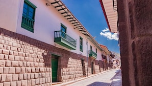 A cobblestone street lined with buildings featuring traditional architecture, including balconies and a brick facade. - ANAHUARQUE (Cusco)