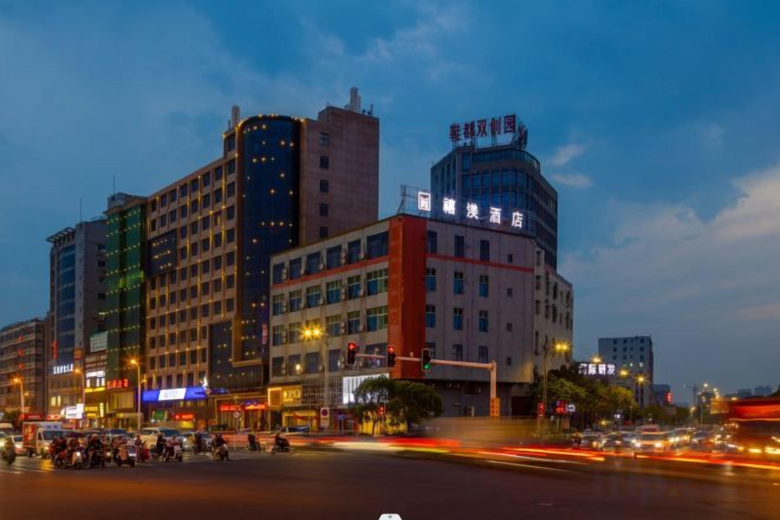 A multi-story hotel with a prominent signage, a busy street in the foreground, and a clear sky.