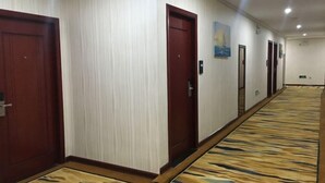 Un pasillo de hotel con puertas de madera, una alfombra estampada y un cuadro en la pared.