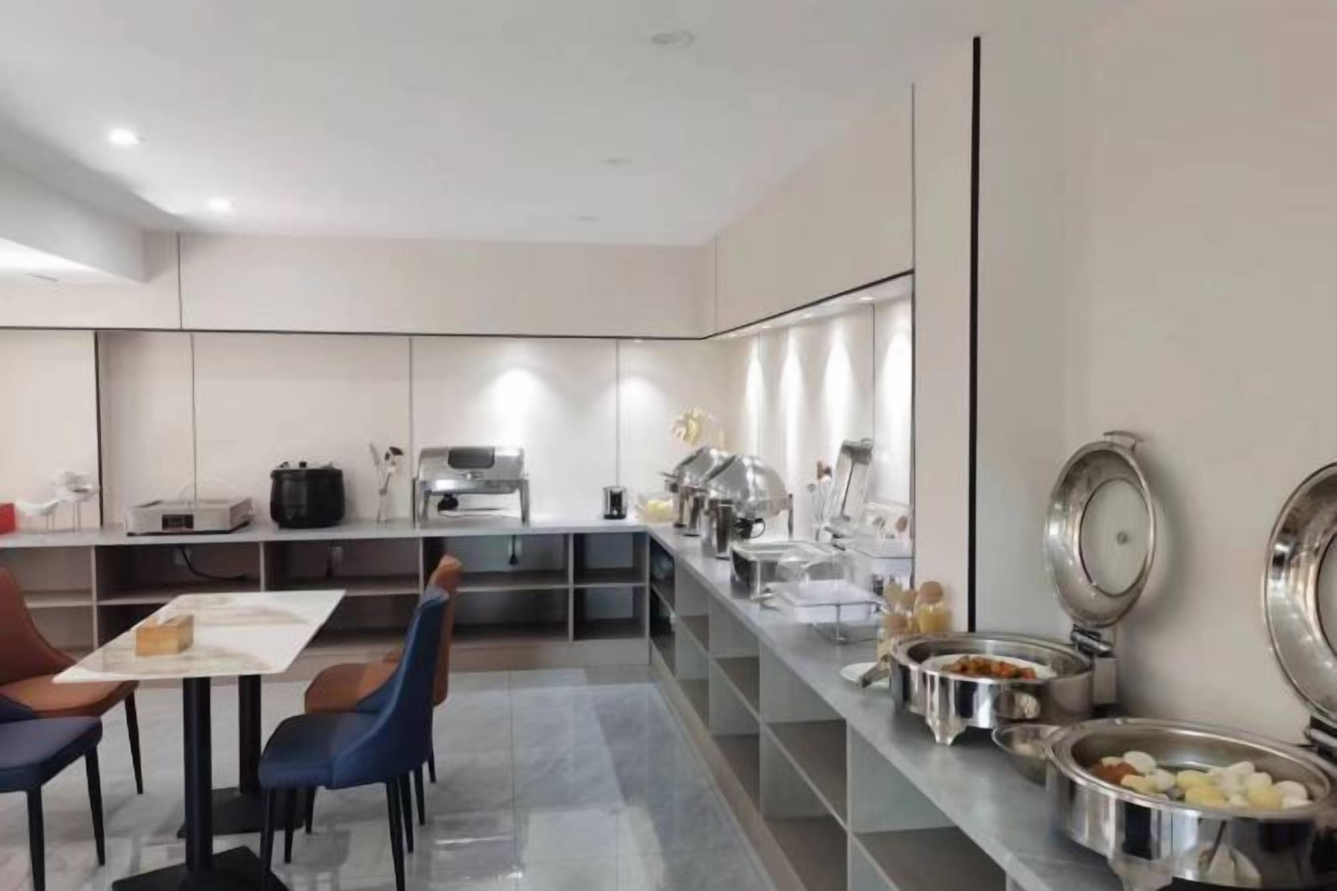 A modern kitchen with a dining area, equipped with stainless steel appliances and a buffet setup.