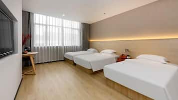 A hotel room with a large window, a desk, and two beds.